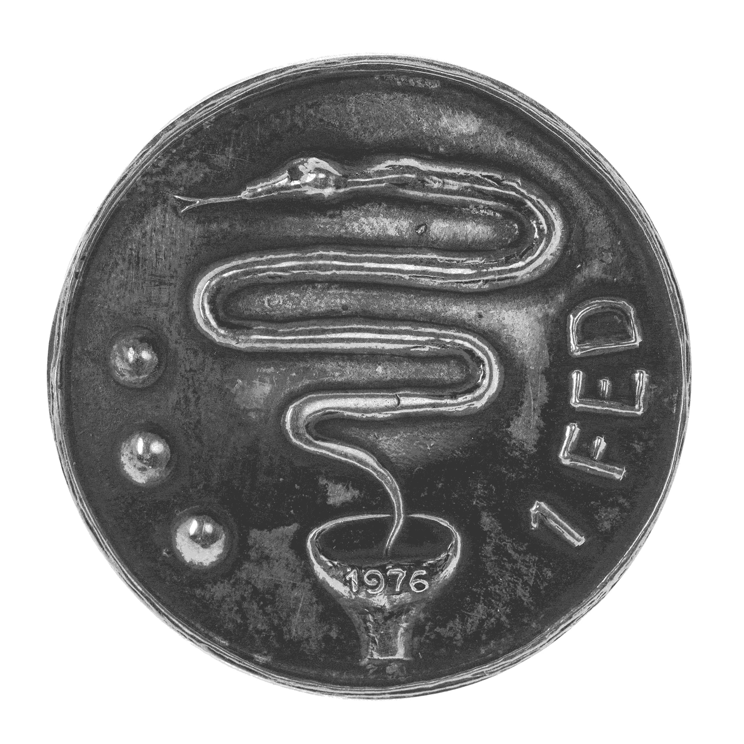 A silver coin with darkened oxidation in areas. At the bottom of the coin is the top of a chillum, up from which rises a plume of smoke in the form of a snake. On the chillum’s edge is the year: “1976.” Left of the snake, three dots (Christiania’s symbol) are seen; and to the right, the inscription: “1 FED.”